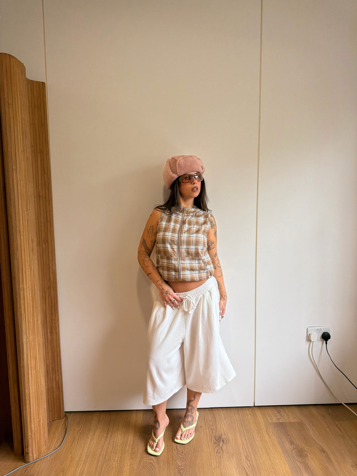 Checked hooded top with oversized white jogger jorts and a fluffy pink hat.