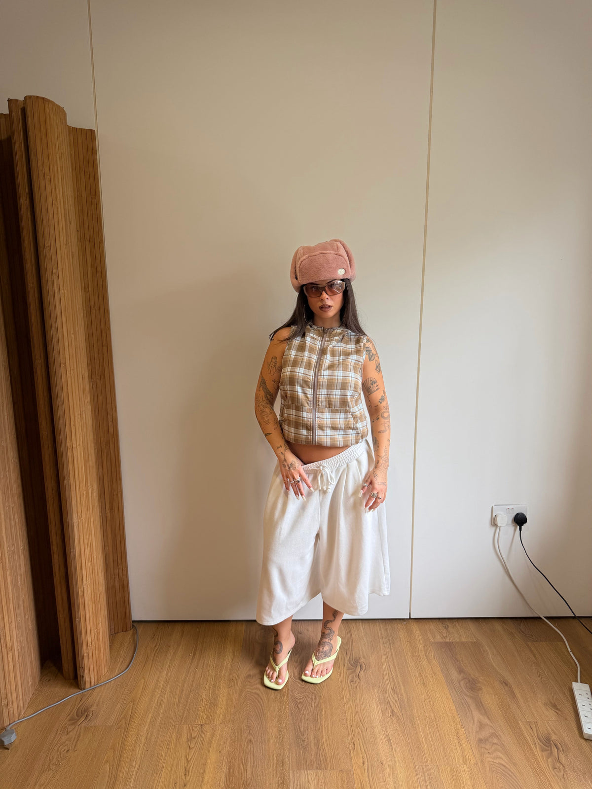 Checked hooded top with oversized white jogger jorts and a fluffy pink hat.