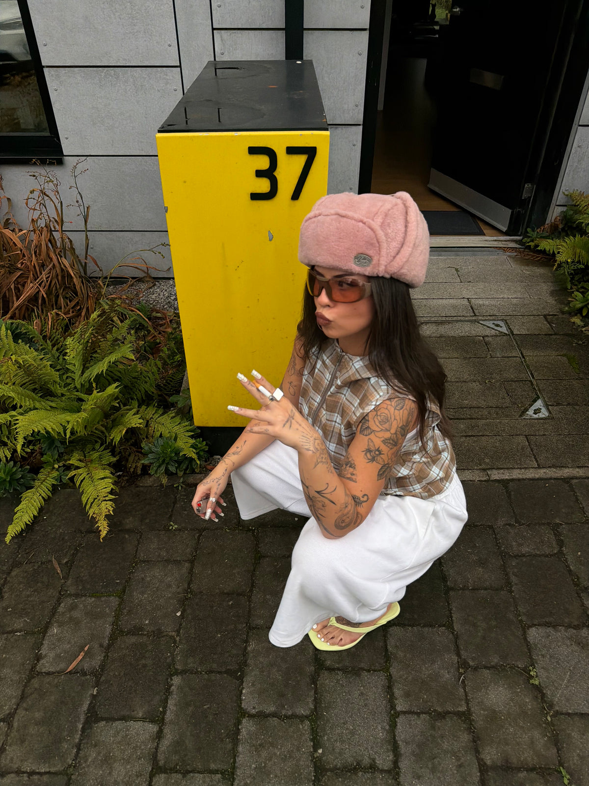 Checked hooded top with oversized white jogger jorts and a fluffy pink hat.