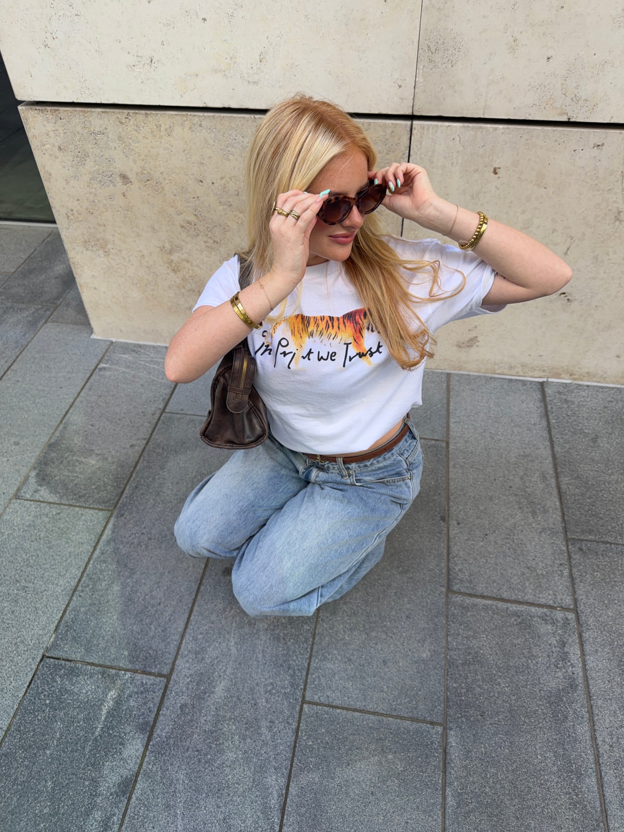 In Print We Trust Tiger Classic Tee styled with blue jeans and a shoulder bag.